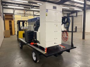white fume extraction system on a black trailer pulled by a yellow forklift in a warehouse